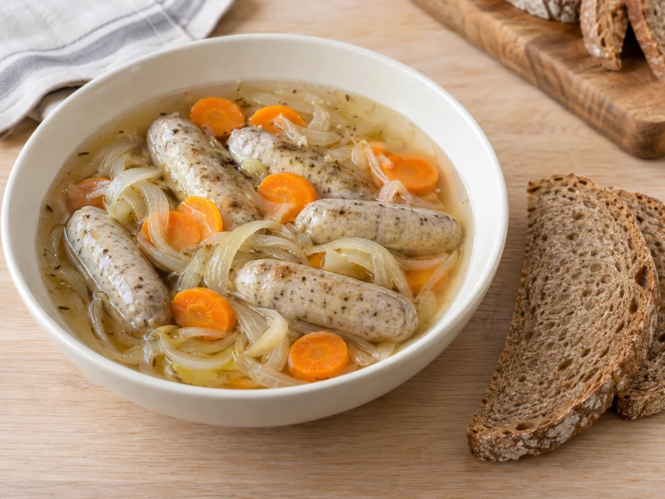Je sechs Saure Zipfel mit Gemüse, Sud und Brot anrichten.